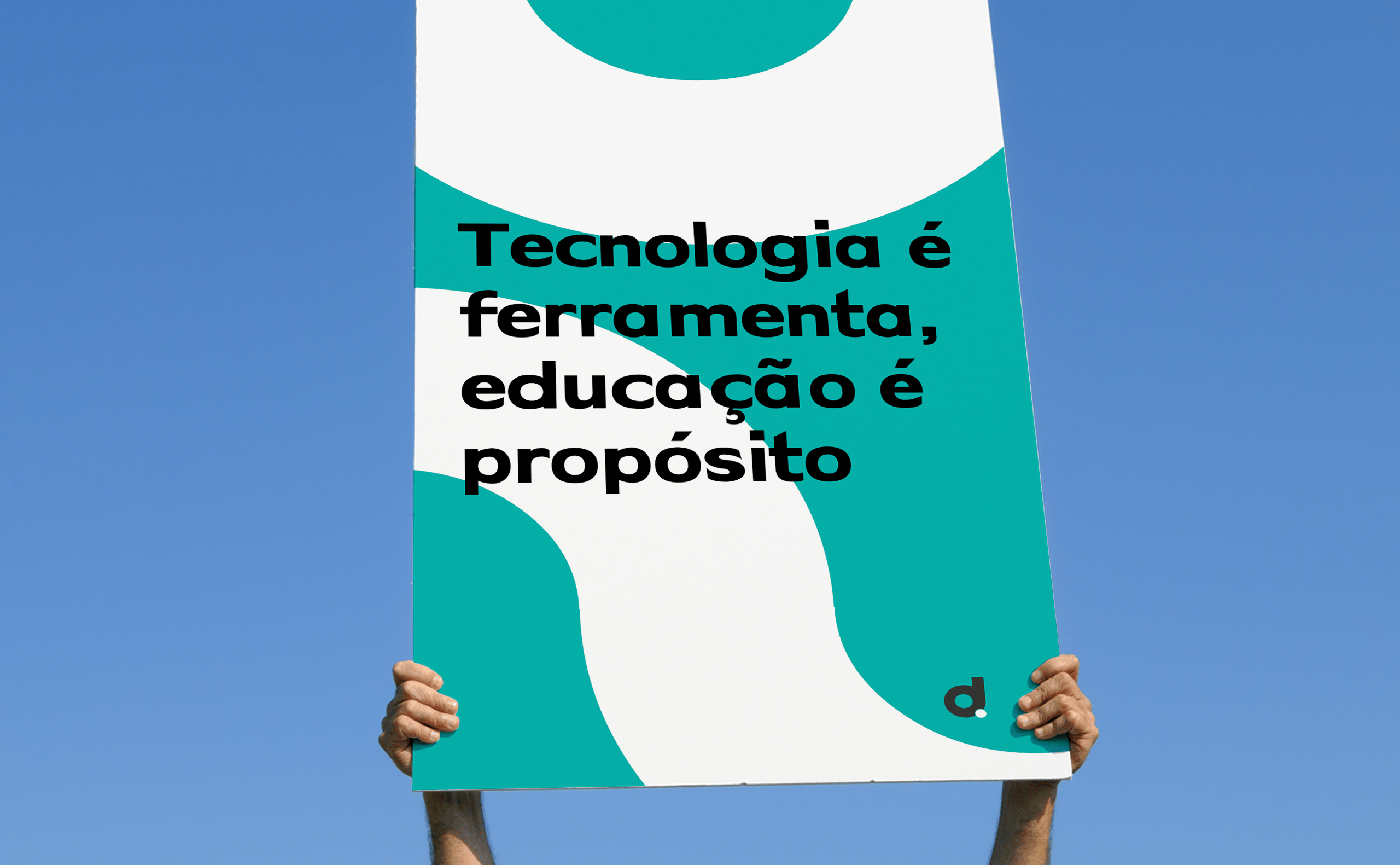 imagem de uma placa sendo segurada pelas duas mãos de uma pessoa que não aparece na imagem, com os seguintes dizeres na placa "tecnologia é ferramenta, educação é propósito"