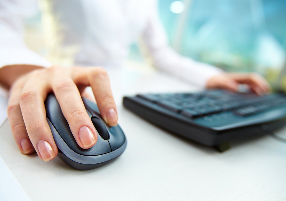 imagem close das mãos de uma pessoa branca utilizando um mouse e um teclado