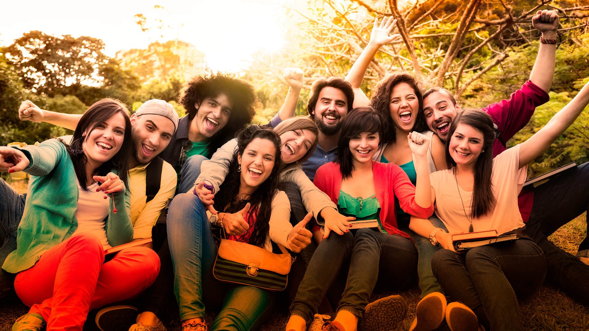 um grupo composto por jovens, homens e mulheres, de diferentes etnias, todos sorrindo