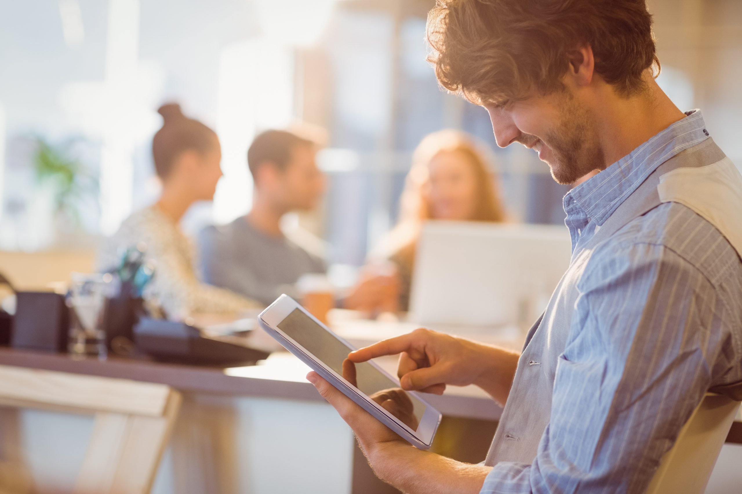 homem jovem, branco, utilizando um tablet em um ambiente casual